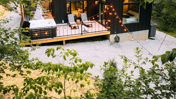 Eine moderne Holzhütte mit einer Terrasse, umgeben von Bäumen.