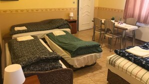 Hotellihuone, jossa on kaksi sänkyä, ruokapöytä, tuoleja, televisio ja ovi.