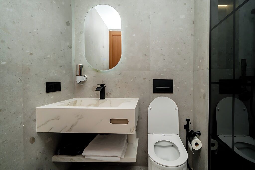 Une salle de bain moderne avec un lavabo en marbre, des toilettes et un miroir.