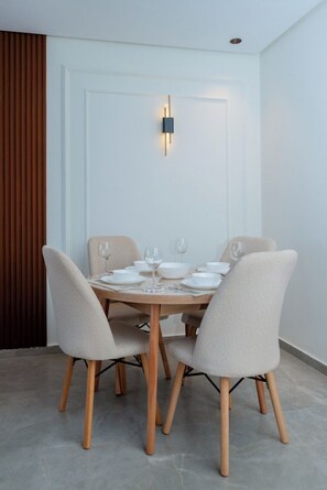 A dining area with a round table, four chairs, and a wall-mounted light fixture. - Central Casablanca – Spacious 2‑Bedroom with Terraces (Casablanca)