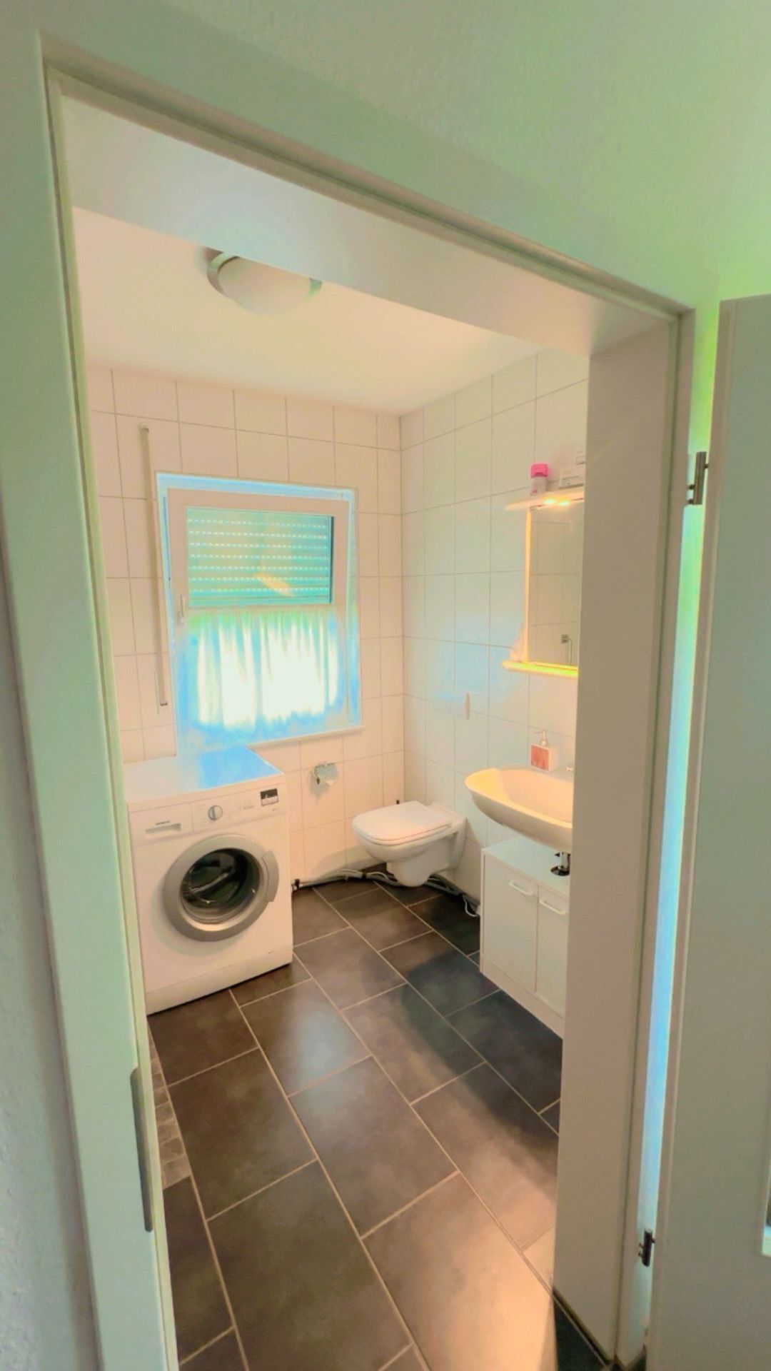 Ein kleines Badezimmer mit Waschmaschine, Toilette und Waschbecken.