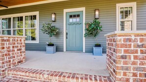 A house with a front porch, a blue door, and two potted plants. - Stylish 4BR near Avondale Restaurants | Sleeps 10 (Birmingham)