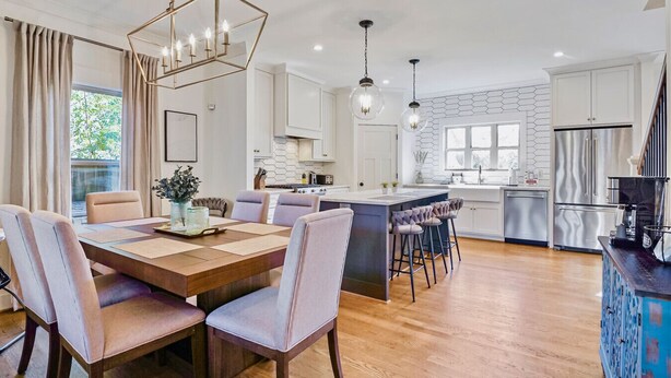 A modern kitchen with a central island, pendant lighting, and a dining area with a wooden table and cushioned chairs. - Stylish 4BR near Avondale Restaurants | Sleeps 10 (Birmingham)
