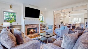 A modern living room with a fireplace, sofas, a coffee table, and a dining area. - Stylish 4BR near Avondale Restaurants | Sleeps 10 (Birmingham)