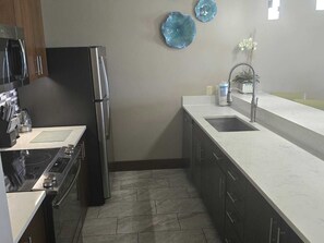 Une cuisine compacte équipée d’un réfrigérateur, d’une cuisinière, d’un évier et ornée d’assiettes décoratives accrochées au mur.