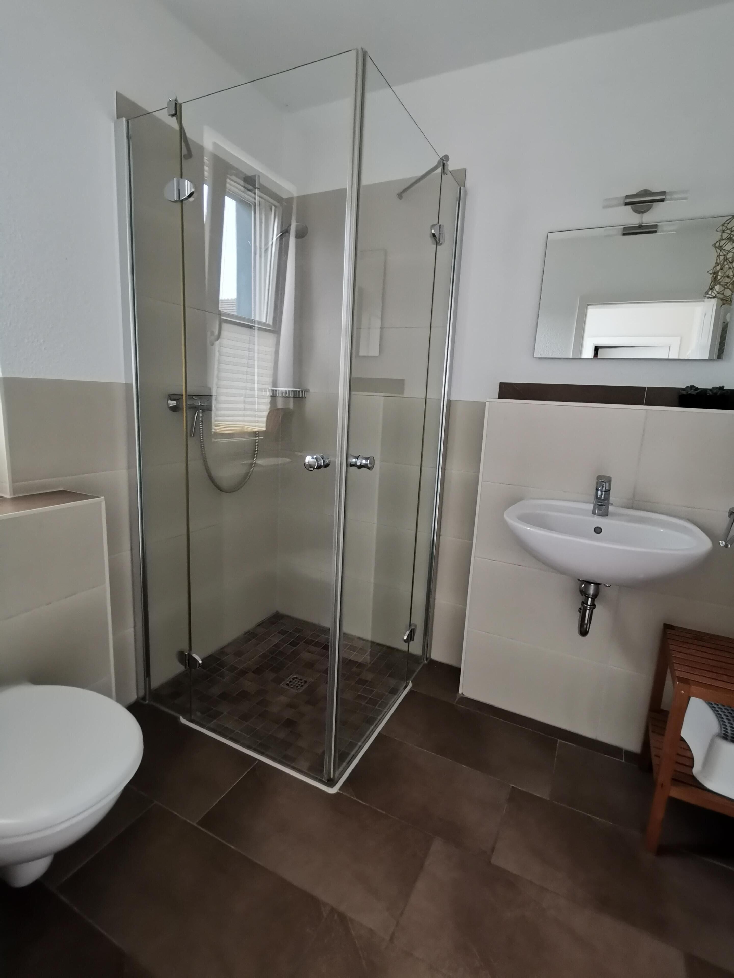 Une salle de bain moderne avec une douche à parois de verre, un lavabo blanc et des toilettes.