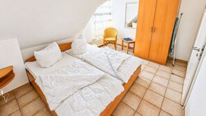 Un dormitori amb un llit, una cadira, un armari i un radiador.