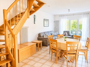 A modern interior with a wooden staircase, a dining area with a table and chairs, a sofa, and a radiator. - Vacation home Mannis Insel - Zingst. Peace, nature and the beach (Zingst)