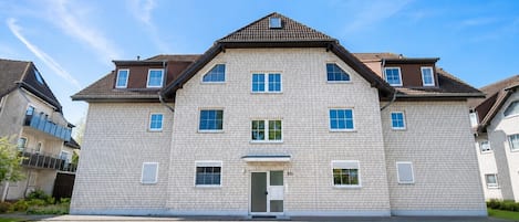 En flervåningsbostadsbyggnad med en symmetrisk fasad, en central entré och en fasad av tegel.