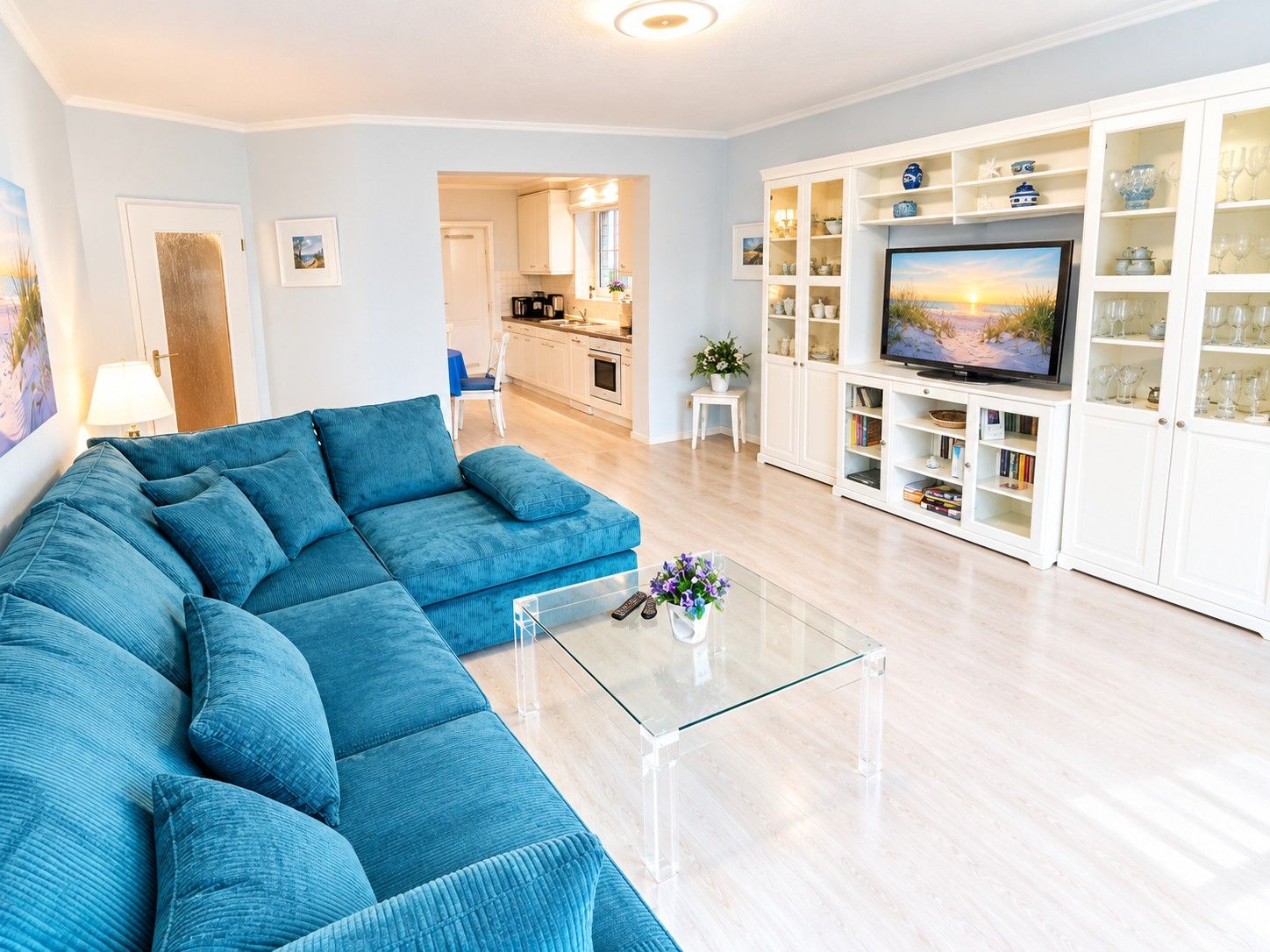 A modern living room with a sectional sofa, a glass coffee table, and a TV on a cabinet.