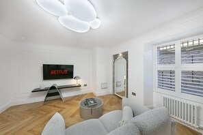 A modern living room with a flat-screen TV, a round coffee table, and a comfortable seating area.
