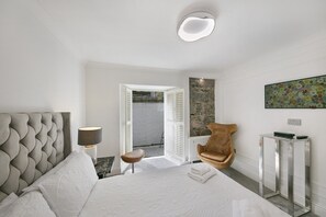 A modern bedroom with a large bed, a chair, a bedside table, and a radiator. - Crown Street Suite 1 - Grampian Lettings (Aberdeen)