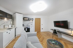 A modern living space with a kitchen, a sofa, a coffee table, and a TV mounted on the wall.