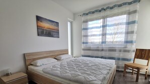 Un dormitorio con cama de madera, mesita de noche, una silla y una ventana con cortinas a rayas.