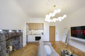 A modern living room with a fireplace, a sofa, and a flat-screen TV. - Crown Street Suite 2 - Grampian Lettings (Aberdeen)