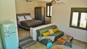 Una camera compatta con un letto, un divano, un tavolino e angolo cottura.