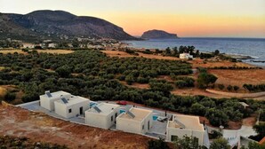 Un borgo costiero con edifici bianchi, una strada e vista sul mare e sulle montagne.