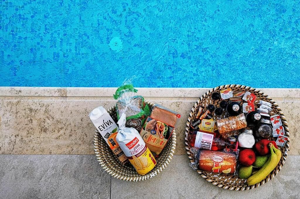 Two baskets of groceries by a poolside.