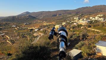 Um telescópio apontado para uma paisagem montanhosa com edifícios ao longe.