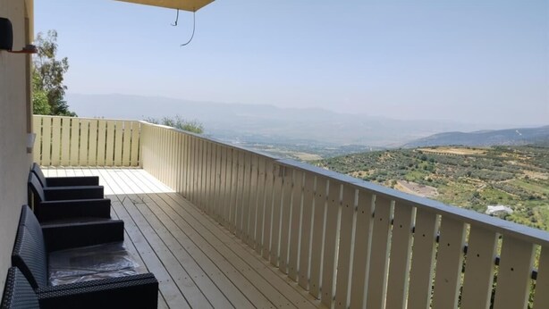 A wooden deck with steps leading to a balcony overlooking a valley.