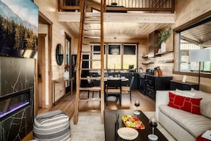 A modern log cabin interior with a dining area, kitchen, and a cozy living space. - Romantic + Luxury Cabin • Hot tub, views and more! (Sevierville)