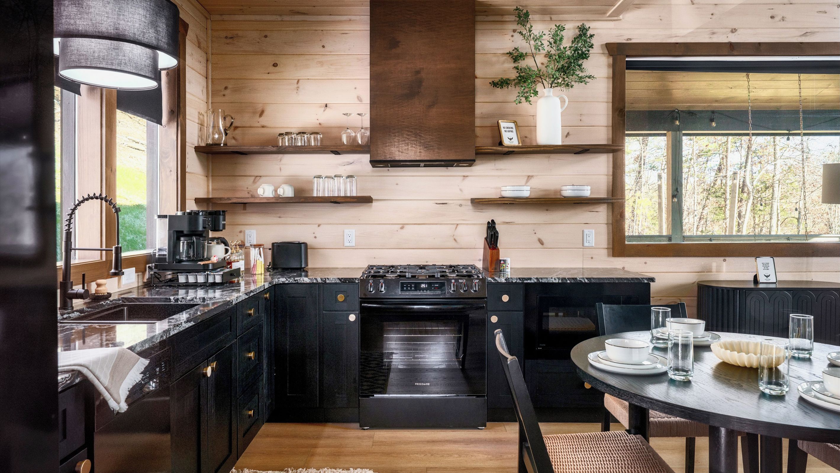 A modern kitchen with a built-in oven, a coffee station, and a dining area with a round table.