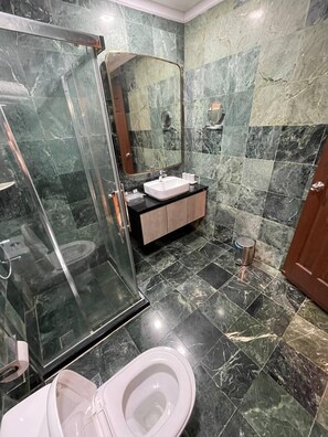 Ein modernes Badezimmer mit einer Duschkabine, einem weißen Waschbecken und einem marmorbelagten Boden.