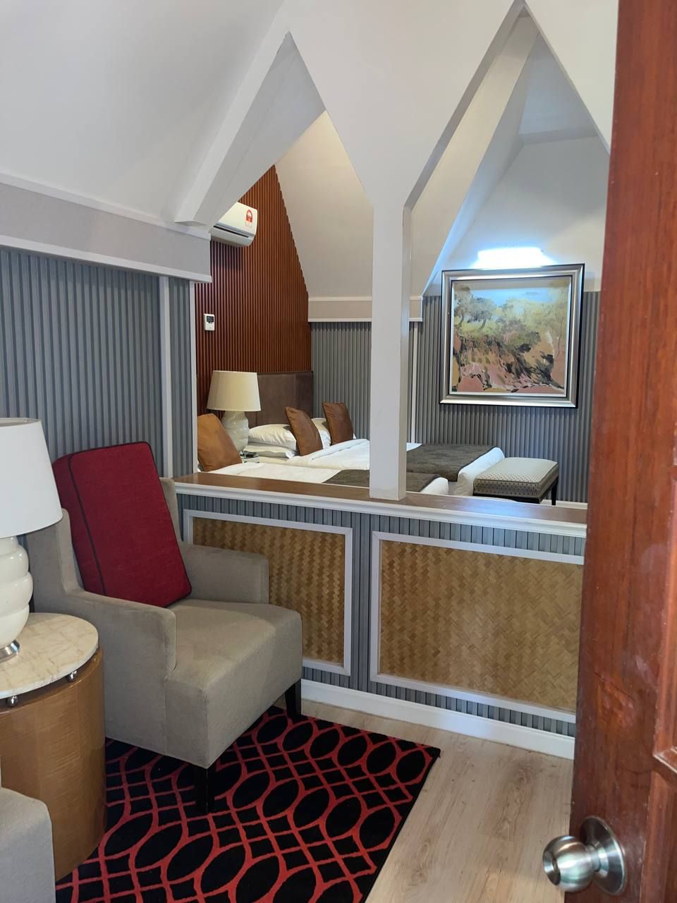 Une chambre d’hôtel avec un lit, un bureau, une chaise, une lampe et un tableau au mur.