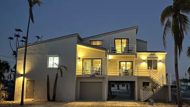 A modern two-story house with a garage, a balcony, and a staircase leading to the upper level. - Casa Bella A in Fort Myers Beach (Fort Myers Beach)