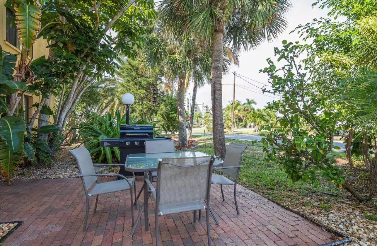 An outdoor patio with a grill, chairs, and a table.