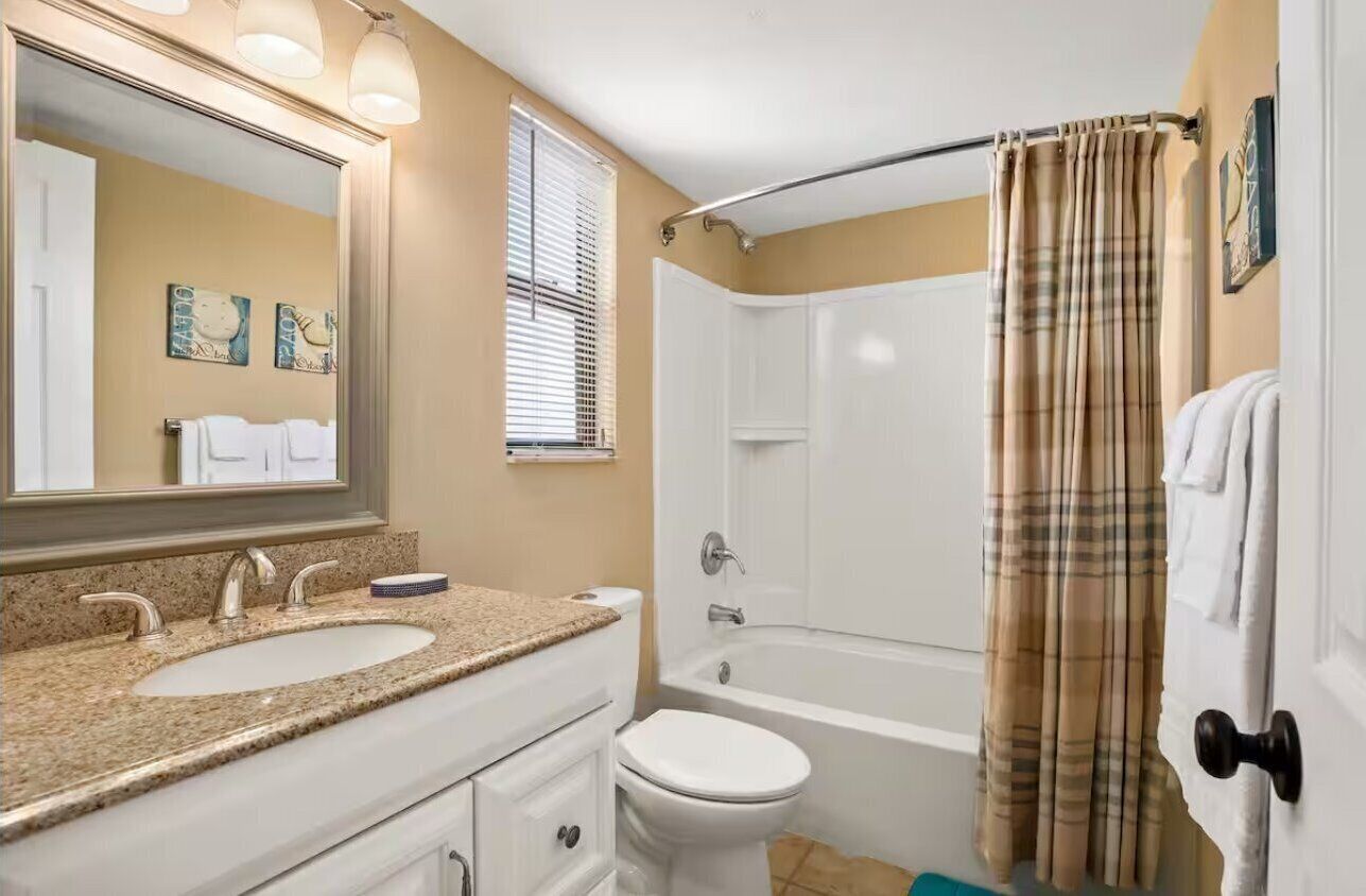 A bathroom with a double sink, toilet, and bathtub.