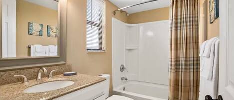 A bathroom with a double sink, toilet, and bathtub.
