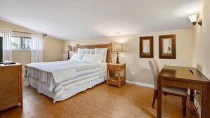 A bedroom with a bed, bedside table, lamp, chair, and a small table. - Casa Bella A in Fort Myers Beach (Fort Myers Beach)