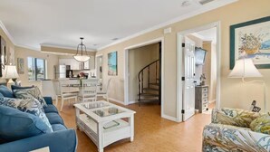 A spacious living room with a blue sofa, a glass coffee table, and a staircase leading to another level. - Casa Bella A in Fort Myers Beach (Fort Myers Beach)