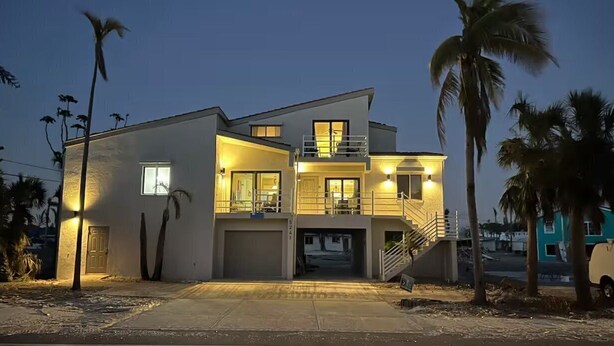 Una casa moderna de dos pisos amb garatge, un balcó i una escala que condueix al pis superior.