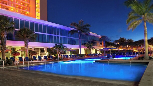 A hotel with a pool area, palm trees, and a well-lit building facade. - Resort with 2 bedrooms and AC in lovely Marco Island (Marco Island)