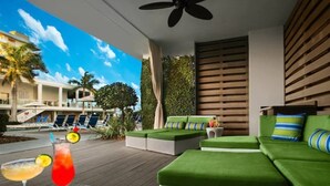 A modern outdoor lounge area with green cushioned seating, a poolside view, and a ceiling fan. - Resort with 2 bedrooms and AC in lovely Marco Island (Marco Island)