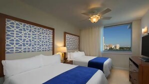 A hotel room with two beds, a ceiling fan, a TV, and a window with a city view. - Resort with 2 bedrooms and AC in lovely Marco Island (Marco Island)