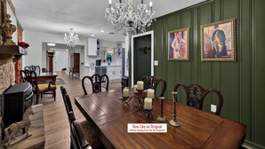 A dining area with a wooden table, chairs, and a chandelier. There are two framed pictures on the wall. - Real Vampire Diaries Props, Walk to Square (Covington)