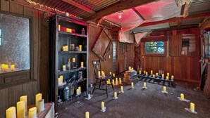 Een rustiek interieur met houten wanden, een boekenplank en kaarsen op de vloer.