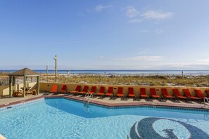 A pool with red chairs, a gazebo, and a view of the beach. - Phoenix III 3159: Beach Access (Orange Beach)