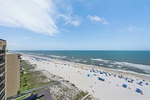 A beach view with a hotel building on the left, a sandy beach with umbrellas, and the ocean. - Phoenix III 3159: Beach Access (Orange Beach)