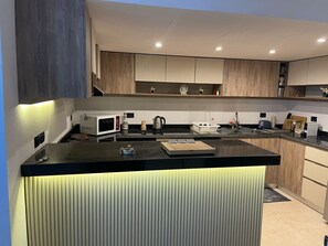 Eine moderne Küche mit Kochinsel, eingebauten Geräten und Holzschränken.