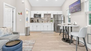 Una cocina moderna con gabinetes blancos, un refrigerador de acero inoxidable y un salpicadero de piedra.