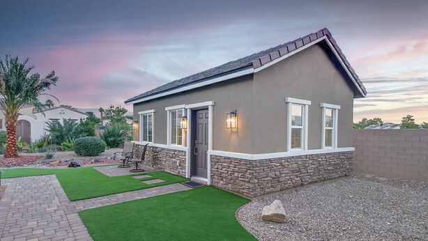 Una casa de un piso con base de piedra y fachada gris.