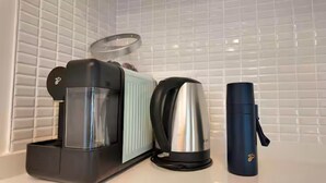 Une cuisine équipée d’une machine à café, d’une bouilloire et d’un thermos posés sur le plan de travail.