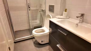 Une salle de bain moderne équipée de toilettes, d’un lavabo et d’une douche.