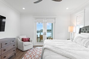A bedroom with a bed, a chair, a dresser, and a view of the outside. - Lakefront with Pool and Gulf Views (Santa Rosa Beach)