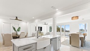 A modern kitchen with a large island, white cabinetry, and a view to the outside. - Lakefront with Pool and Gulf Views (Santa Rosa Beach)