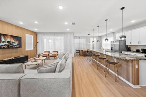 Una sala de estar moderna con un sofá, sillas, un televisor y una chimenea.